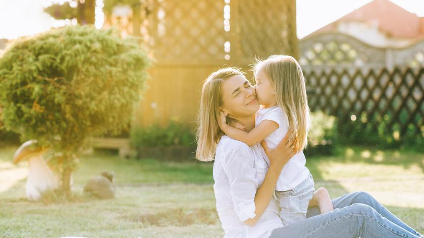 Mama z dzieckiem, siedzą na kocu w ogrodzie