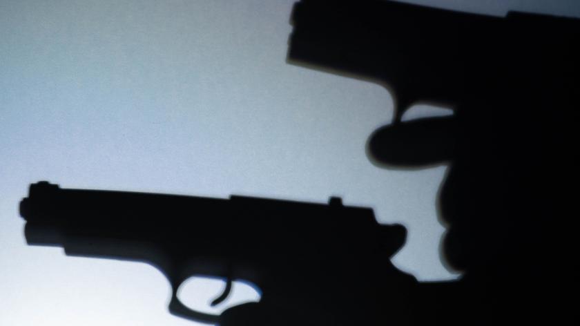 Cień broni na białej ścianie