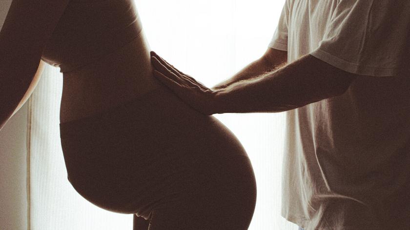 Kobieta w ciąży oparta o mebel