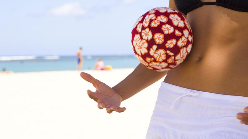 Plażowiczka w czarnym bikini i białej spódniczce.