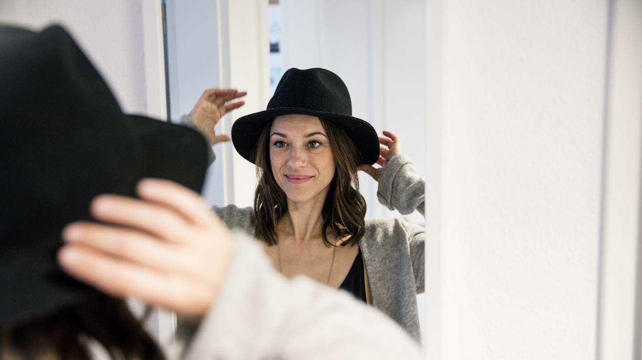 Kobieta przymierza kapelusz i przegląda się w lustrze
