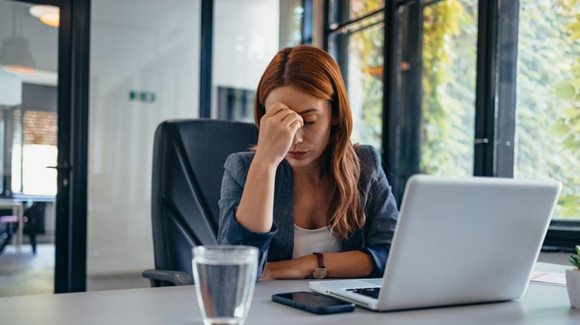 zmęczona kobieta siedzi przy biurku i pracuje