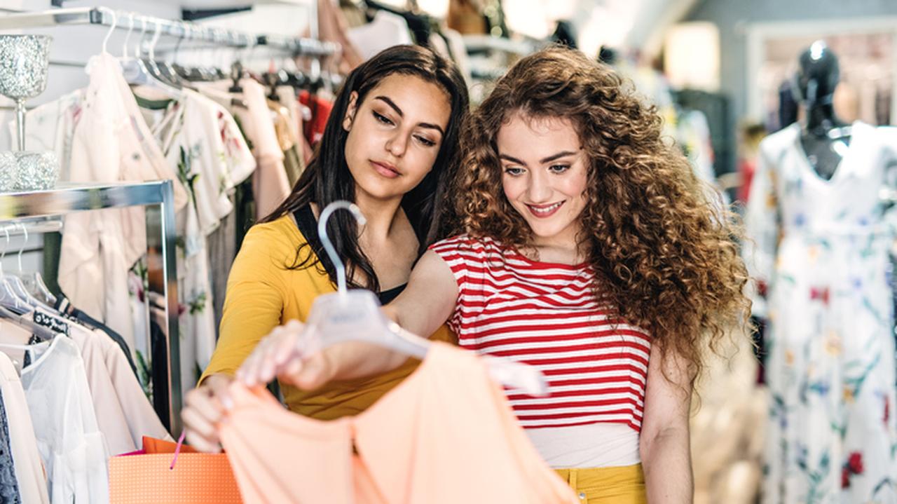 Dwie kobiety oglądające sukienkę w sklepie z odzieżą.