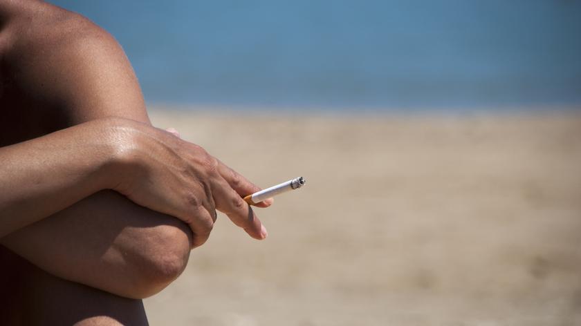 Osoba z papierosem w ręku na plaży