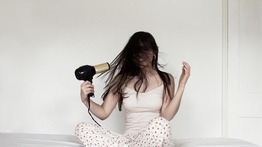 Kobieta suszy włosy suszarką