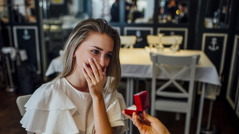 Zaskoczona kobieta przyjmuje pierścionek zaręczynowy