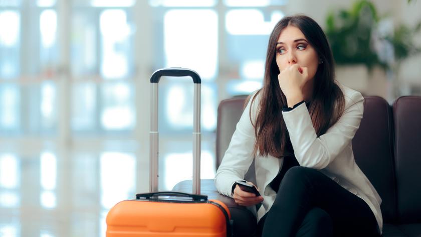 smutna kobieta siedzi z walizką na lotnisku