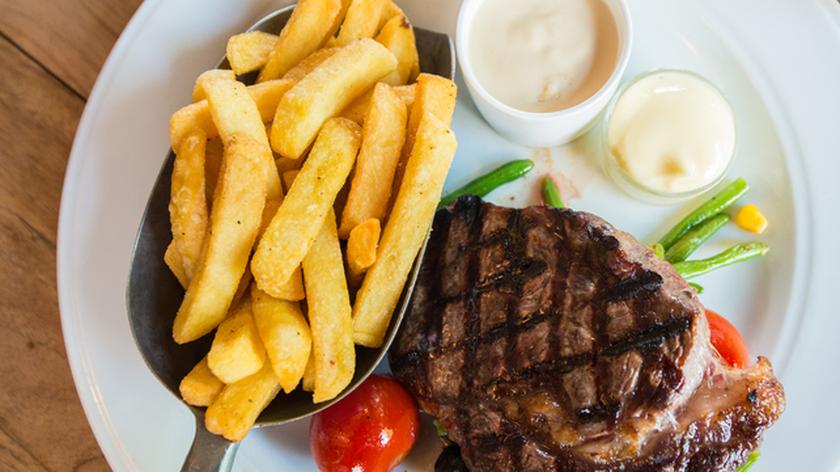 Porcja mięsa, frytki i dodatki w postaci sosów na białym talerzu. Kuchnia holenderska. Przepisy kulinarne