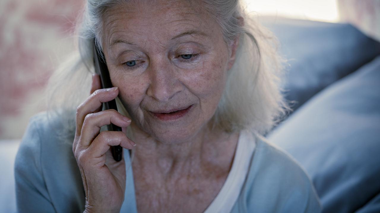 Starsza kobieta z telefonem komórkowym przy uchu. 