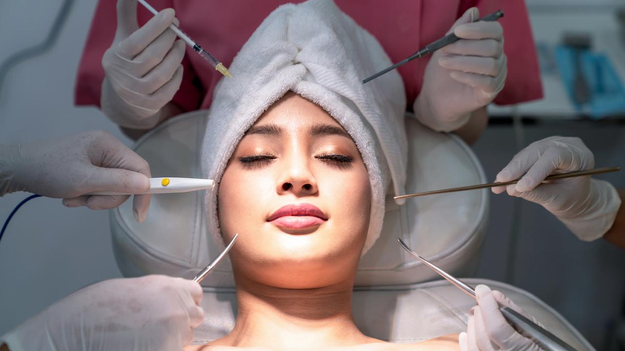 Kobieca twarz otoczona narzędziami chirurgicznymi. Poświęcenie dla urody. 
