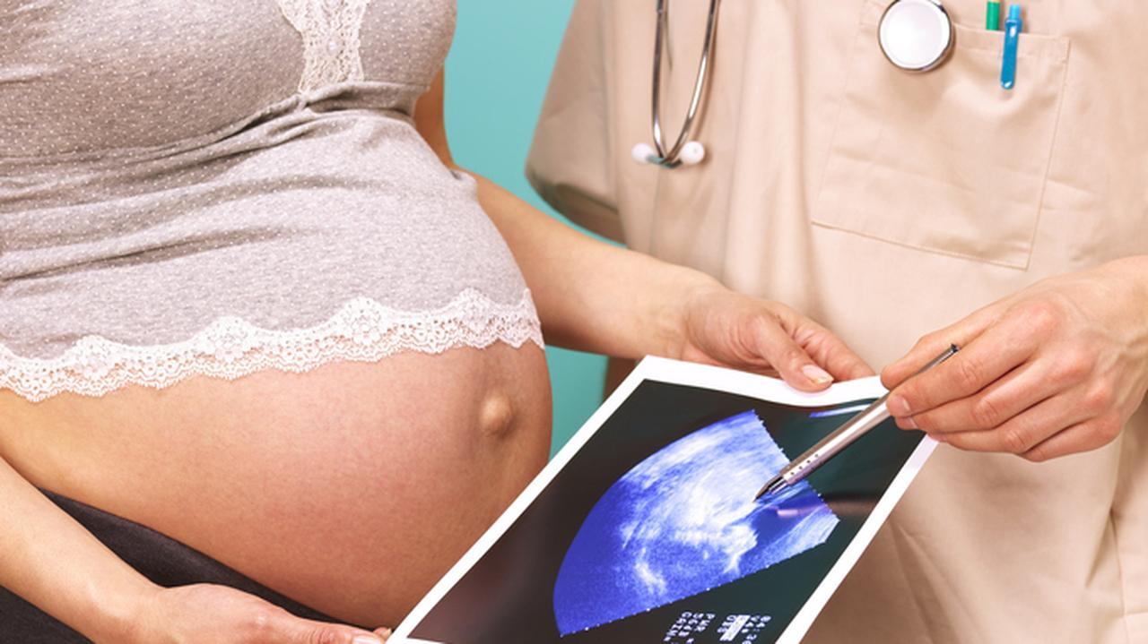 Kobieta w ciąży trzymająca w dłoniach wyniki badania USG. Surogatka.