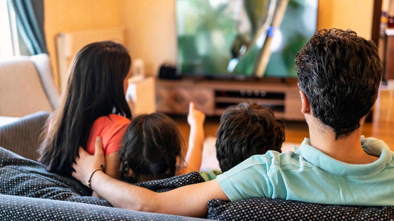 Czteroosobowa rodzina zasiadająca przed ekranem telewizora. 