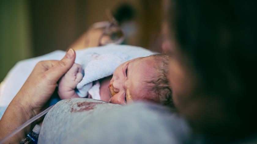 Kobieta w szpitalu trzyma nowo narodzone dziecko