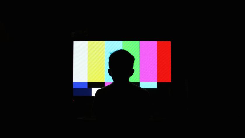 Chłopiec siedzi przed telewizorem, który nie ma sygnału