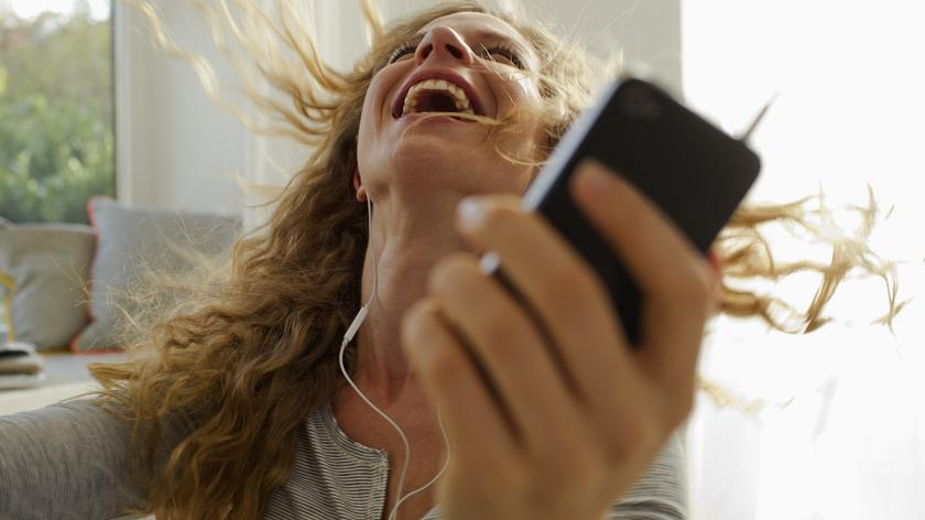 Kobieta z telefonem w ręku się śmieje