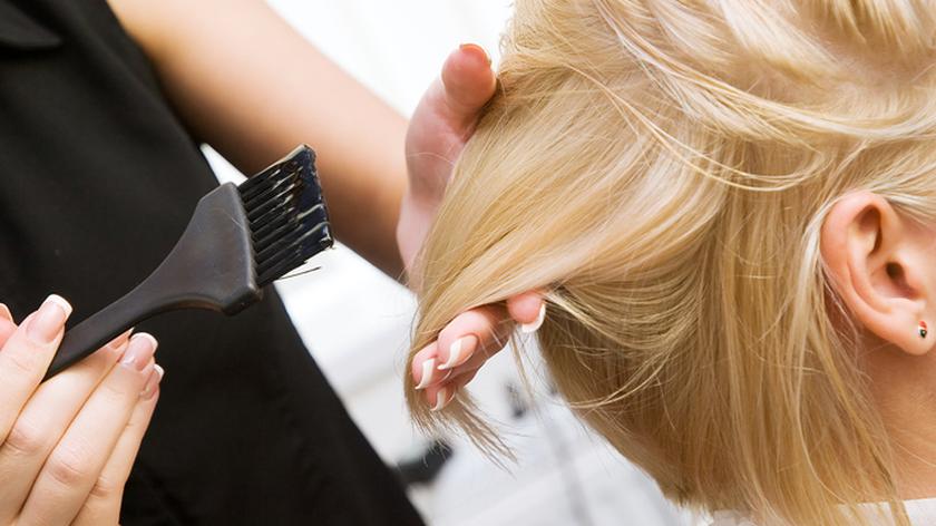 Fryzjerka nakładająca pędzelkiem farbę na włosy klientki. Koloryzacja włosów. Konturowanie włosów. 