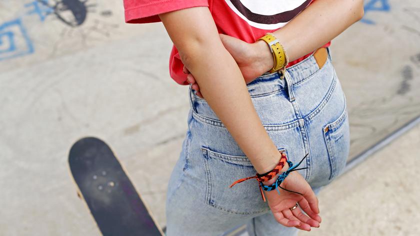 Dziewczyna z deskorolką w różowym podkoszulku z bransoletkami na sznurku