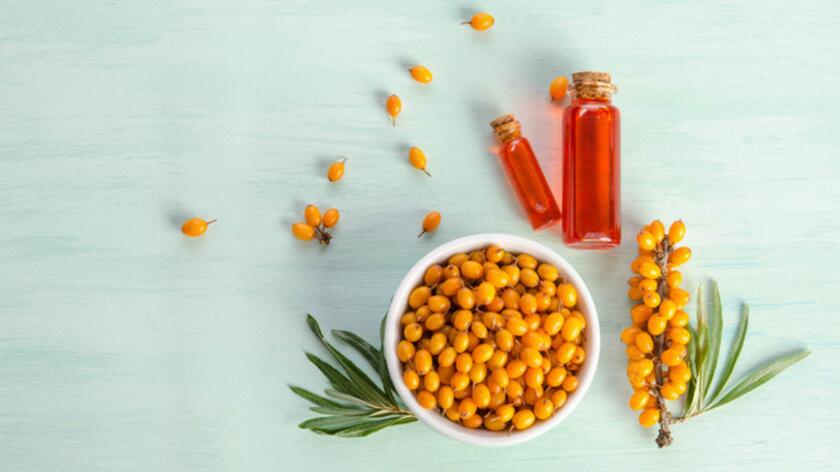 owoce rokitnika w miseczce i olej rokitnikowy w butelkach 