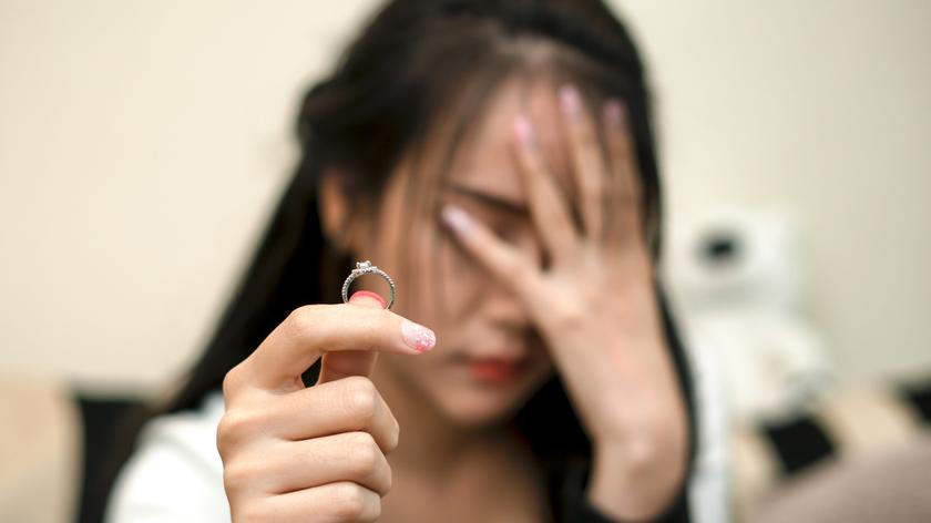Załamana kobieta trzyma w dłoni pierścionek