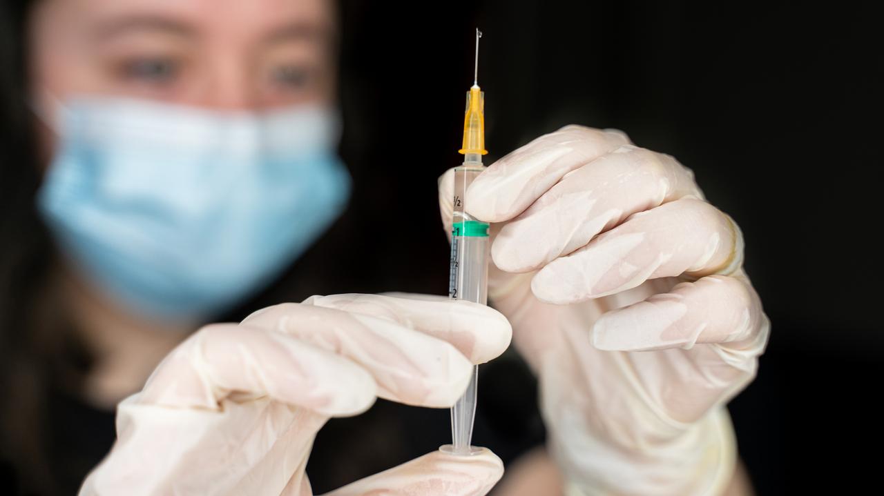 Naukiec trzymający szczepionkę na SARS-CoV-2