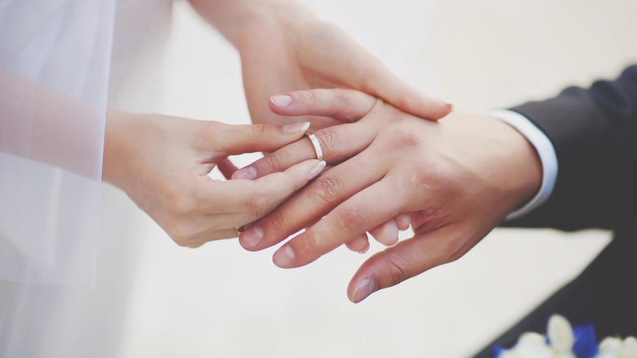 Kobieta wkładająca obrączkę na palec mężczyzny. Ceremonia zaślubin. Zmiana nazwiska po ślubie.