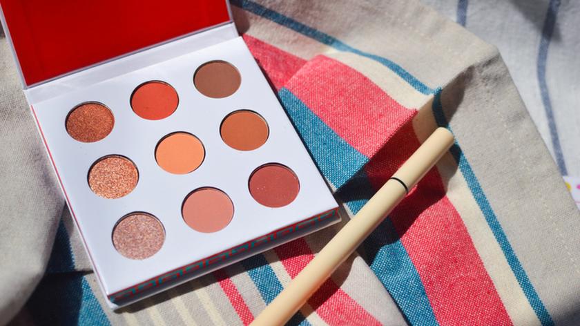 Paleta neutralnych cieni do powiek, obok niej eyeliner w pisaku.