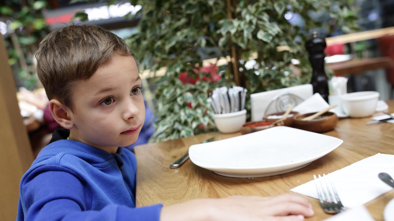 Kilkuletni chłopiec siedzi przy stole w restauracji