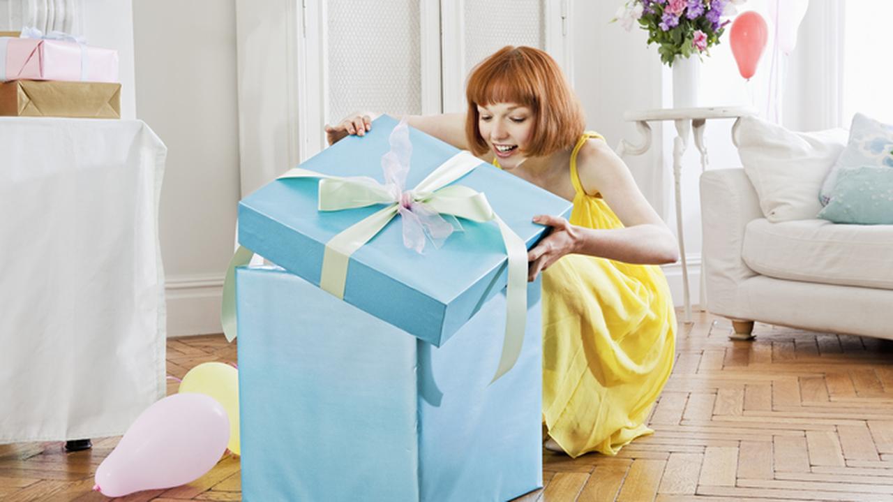 Kobieta otwierająca wielkie prezentowe pudełko. Autoprezent. 