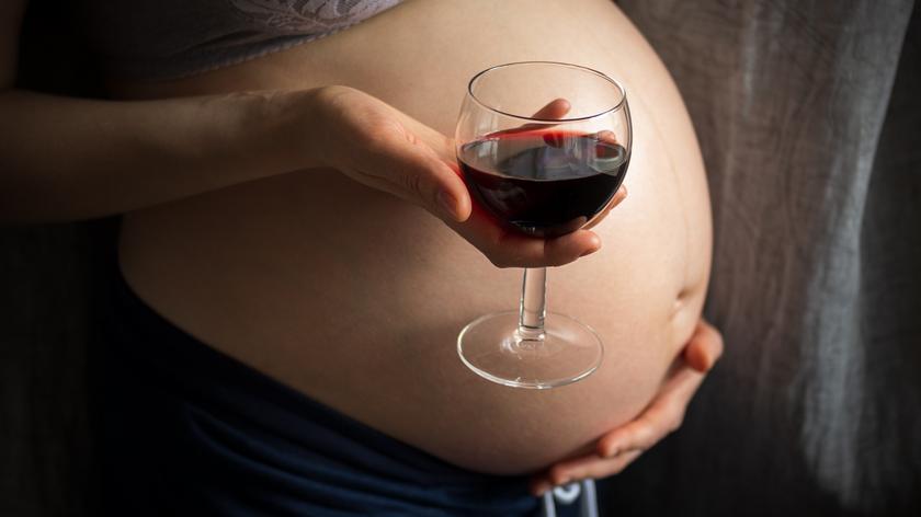 Ciężarna kobieta trzymająca w dłoni kieliszek wina