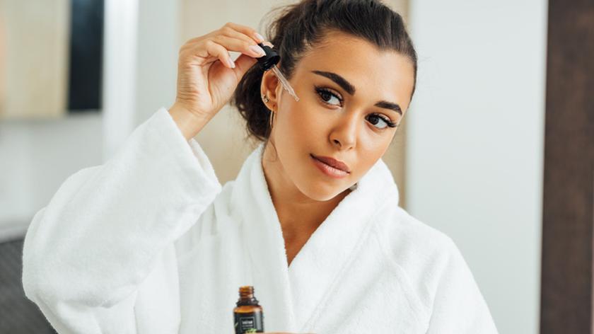 Kobieta nakładająca na twarz pielęgnacyjne serum. Pielęgnacja skóry. Domowa pielęgnacja. Retinol. Retinol sandwich.