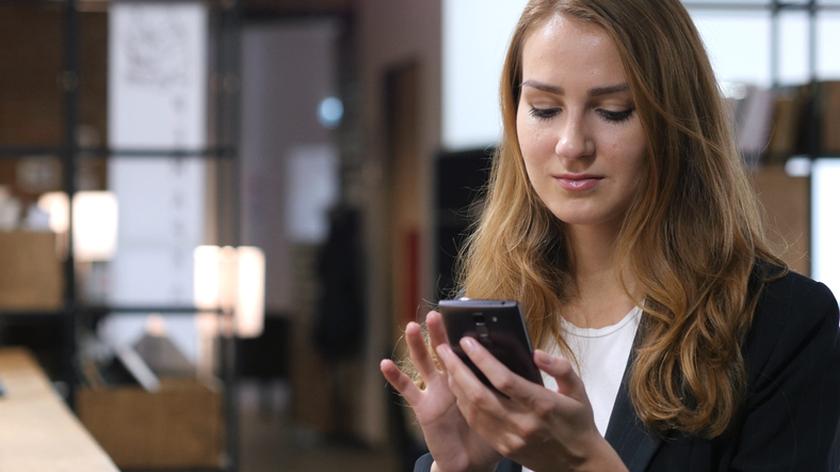 Kobieta wpatrująca się w ekran telefonu. Media społecznościowe. Związki.