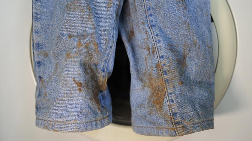 Niebieskie jeansy pokryte brązowymi plamami.