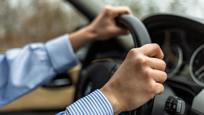 Dłonie na kierownicy samochodowej. 