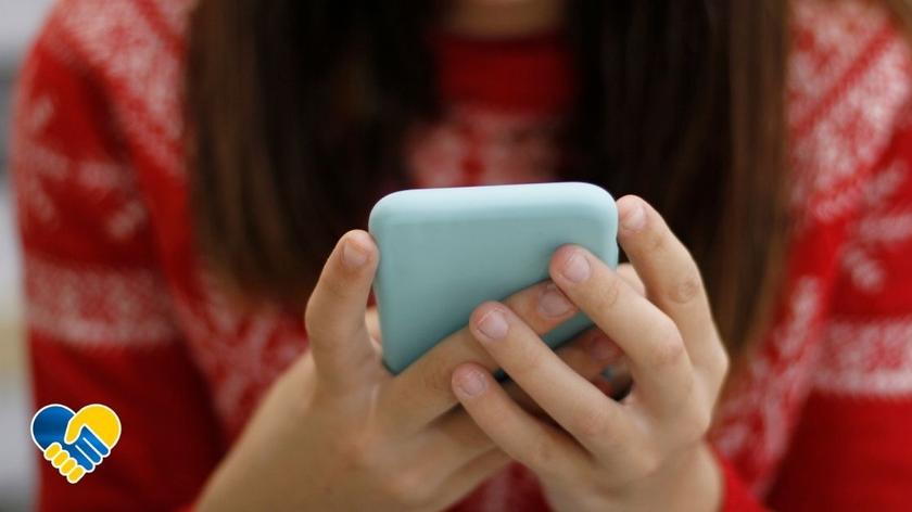 Dziewczyna pochylająca się nad ekranem telefonu. Pomoc dla Ukrainy. Telefon zaufania.