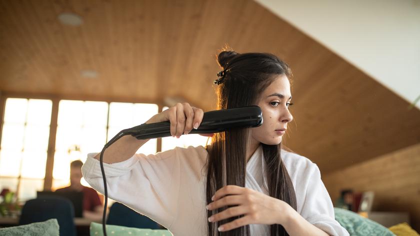 Kobieta prostuje włosy prostownicą