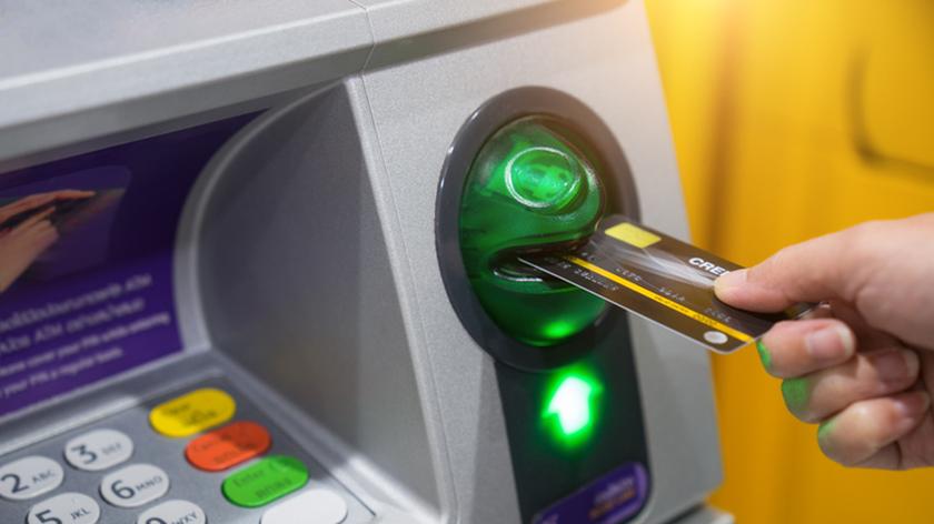 kobieta wkładająca kartę do bankomatu