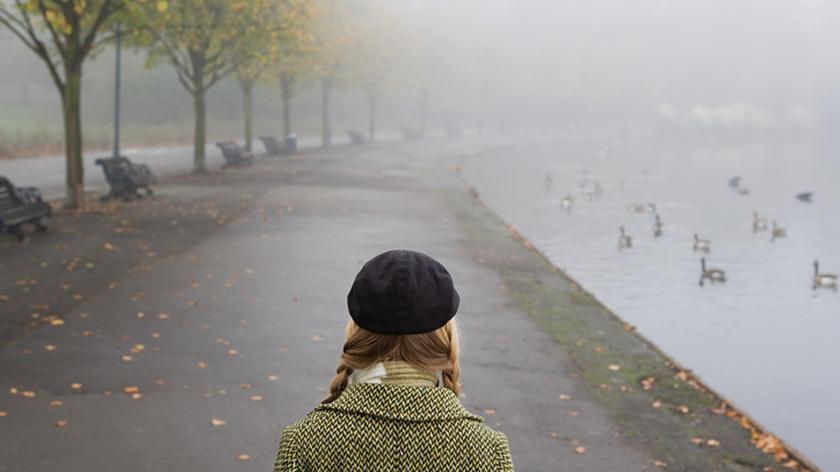 Dziewczyna w czarnym berecie spaceruje po parku jesienią.