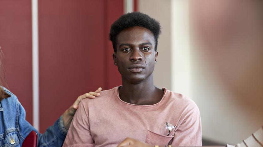 Smutny mężczyzna z kobiecą dłonią na ramieniu