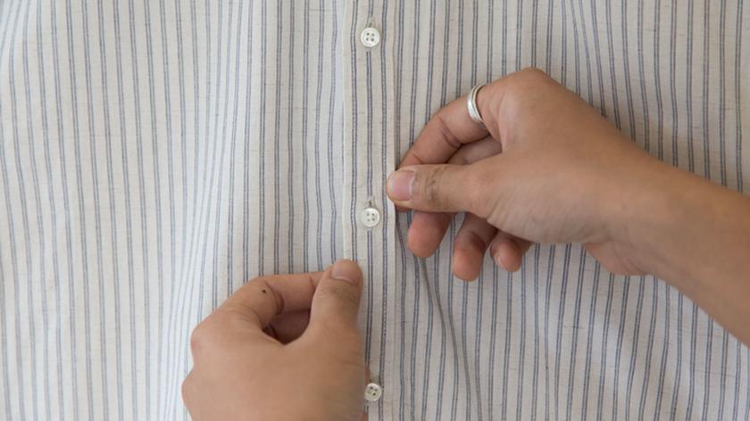 Damskie dłonie na tle pasiastej koszuli. 