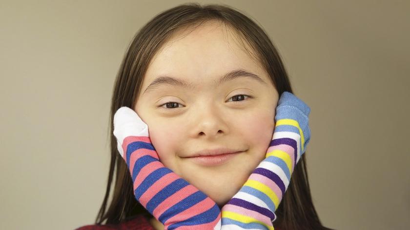 Dziewczynka z zespołem Downa ma na rękach kolorowe skarpetki