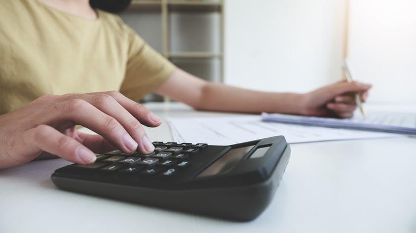 Kobieta oblicza domowy budżet używając kalkulatora