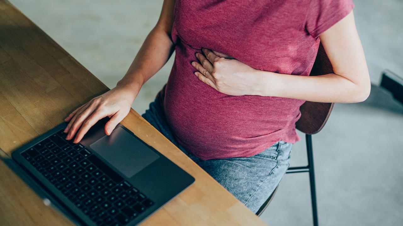 Osoba w ciąży pisząca na laptopie